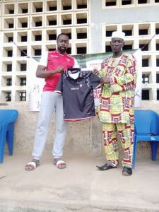 Aboudoulaye Safoua (à gauche) remettant un exemplaire de maillot au chef quartier de Tchawanda (à droite)