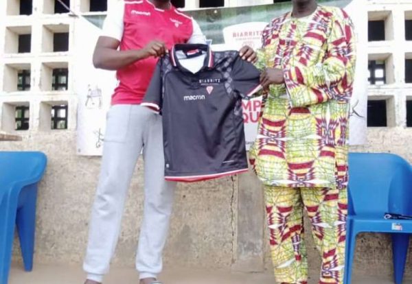 Aboudoulaye Safoua (à gauche) remettant un exemplaire de maillot au chef quartier de Tchawanda (à droite)