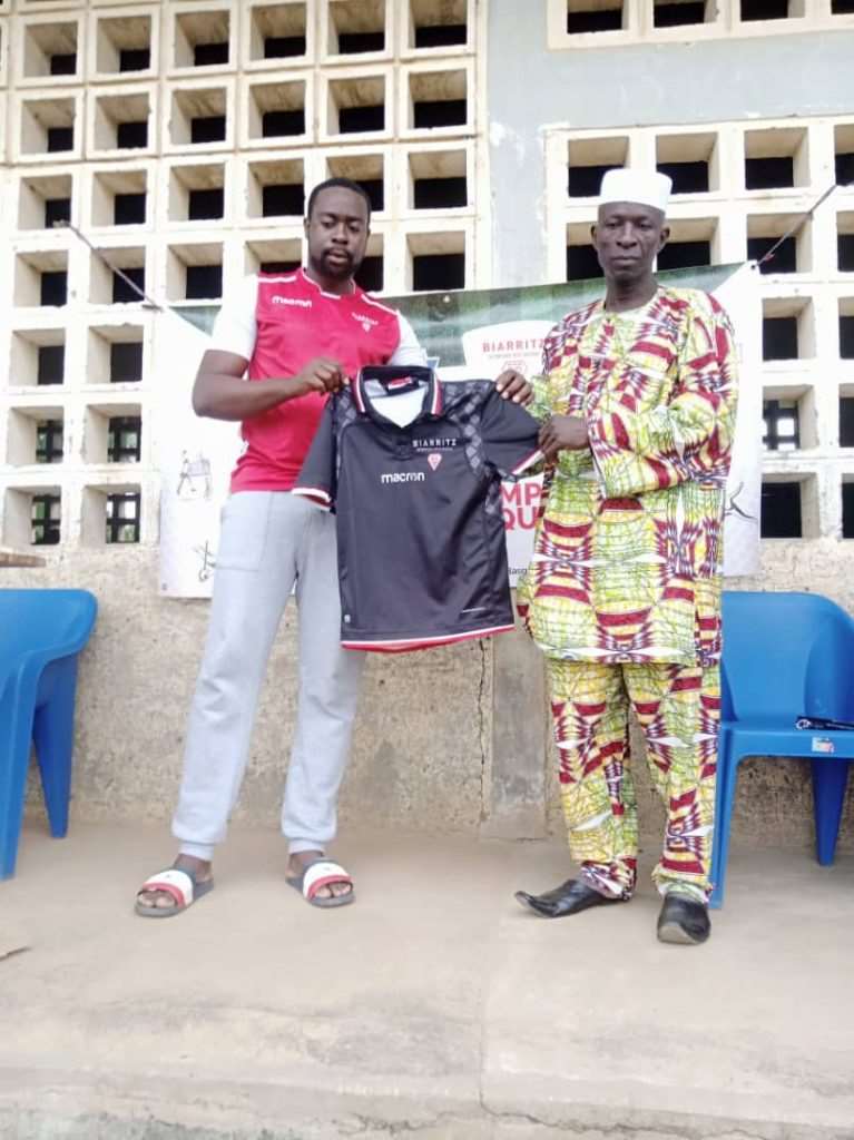 Aboudoulaye Safoua (à gauche) remettant un exemplaire de maillot au chef quartier de Tchawanda (à droite)